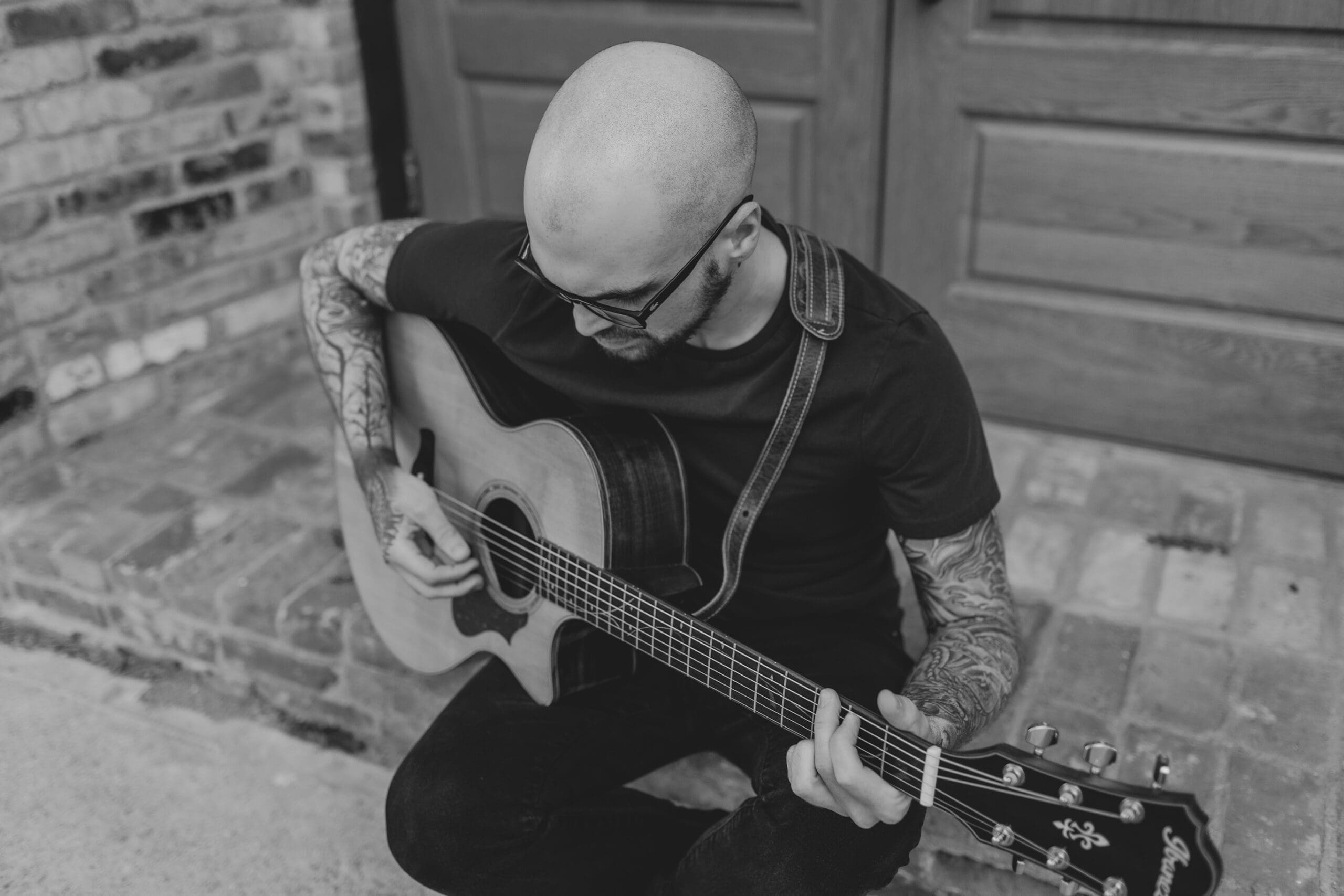 local musician Cody Peek, plays his guitar while sitting on the ground