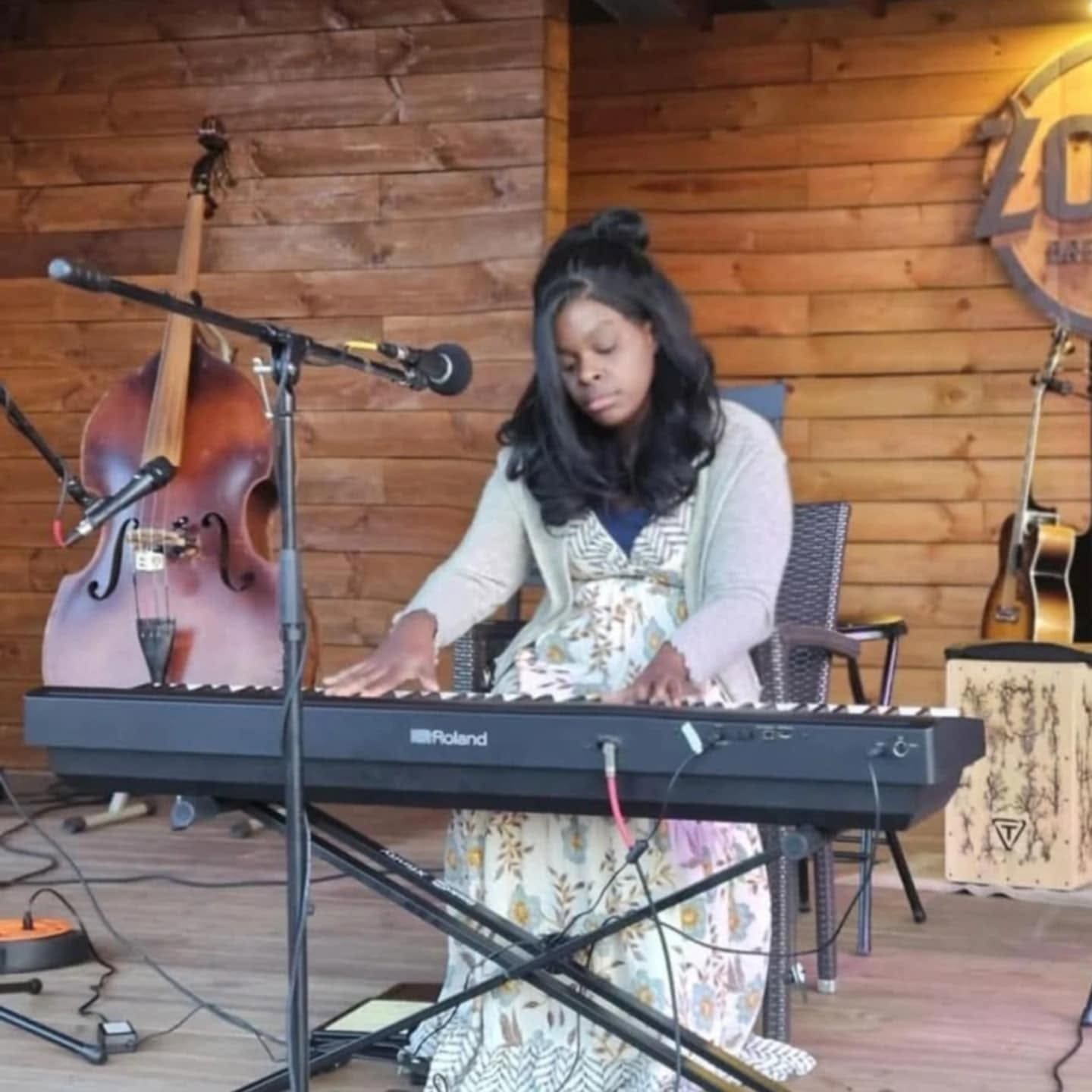 Joyceann Maynard, local musician plays a keyboard infront of a wood panel wall